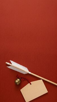 Top view of shinto sacred arrow bell and wooden votive plaque ema on crimson paper vertical