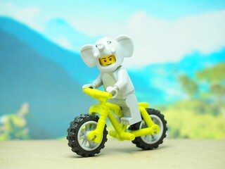 Fototapeta premium Indonesia - October 3, 2023 : Mini toy of action figure at table with blurred background. Toy photography concept. Riding the bicycle conceptual design.