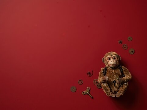 Vintage Mechanical Wind-up Monkey Toy on Red Background Flatlay Banner with Copy Space