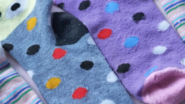 Close up view of colorful baby socks with polka dots and stripes on white background