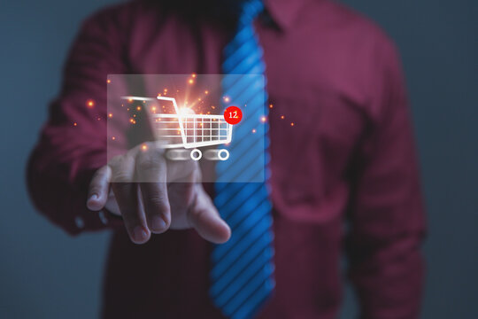 Digital e-commerce shopping, e-commerce concept. Businessman touching a shopping cart icon containing a red notification badge showing twelve items. Innovative corporate retail strategies.