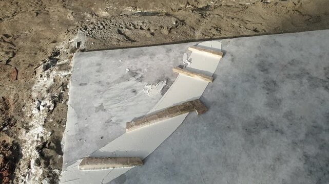 Construction Workers Fitting and Installing  White Marble Slab Floor Tiles on Building Site