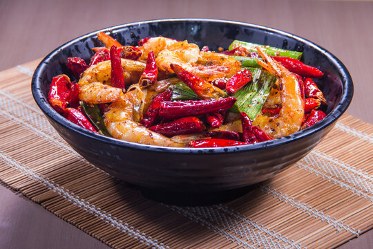 Delicious shrimp stir fry with red chili peppers and vegetables on a wooden table