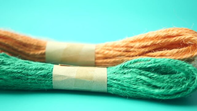 Close up of orange and green jute twine bundles on cyan background