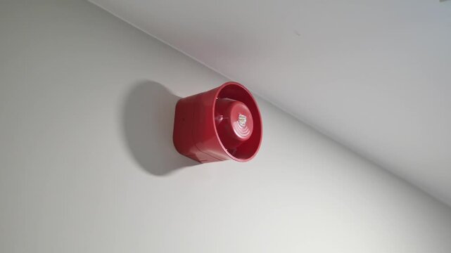 Red fire alarm siren and illuminated green exit sign on ceiling