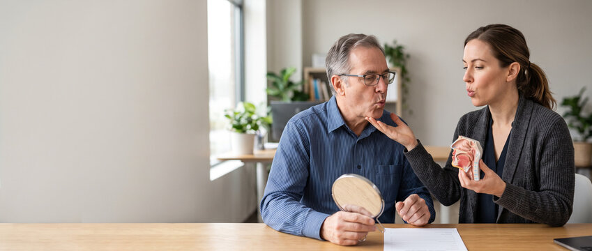 Speech-language therapist guides adult patient through communication rehabilitation exercise, supporting speech recovery, breathing control, neurological care and patient-centered therapy.