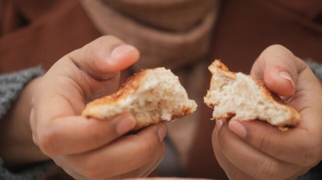 Close up shot of woman tearing apart fresh warm bread with hands showing soft internal texture