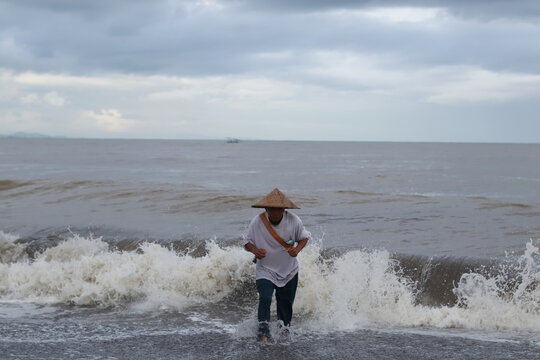 Traditional fisherman returning through rough sea waves on the coast of Lombok, Indonesia.