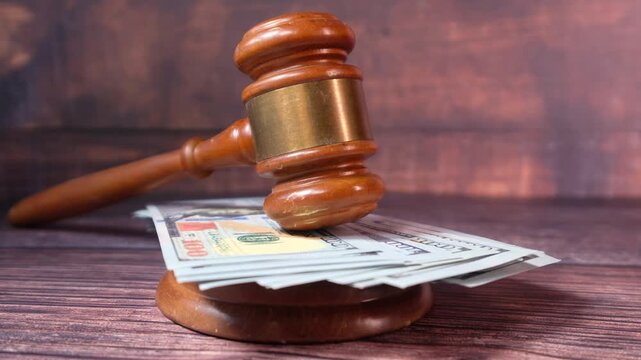 Lawyer gavel striking money on wooden table symbol for justice and financial court decisions