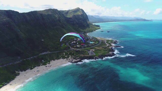 Paraglider flying over the scenic coastline of oahu, hawaii