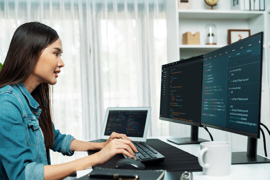 Young Asian in IT developer creating with typing online information on pc with coding program data of website application, wearing jeans shirt. surrounded by safety analysis two screens. Stratagem.