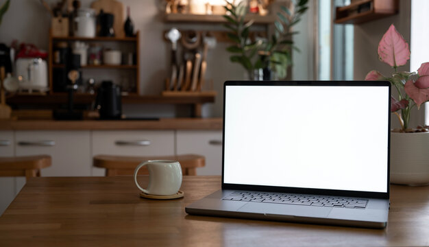 Laptop screen mockup on wooden table in warm kitchen interior
