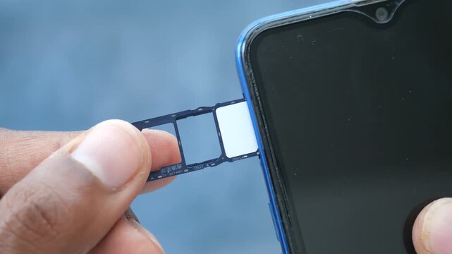 Hand inserts SIM card tray into smartphone slot for network connection and mobile communication