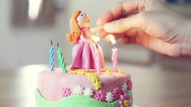 Hand lighting a candle on a birthday cake with a princess topper
