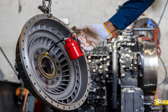 Technician applies lubricating oil using oiler can on torque converter stator in workshop.