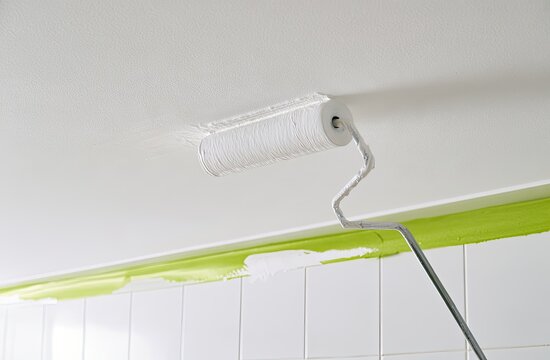 Applying fresh white paint to a textured ceiling with a roller