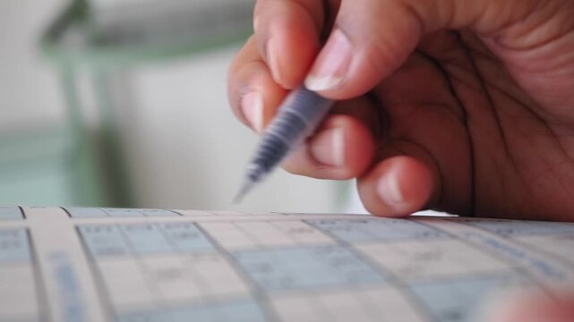 Person Solving a Sudoku Puzzle with a Pen