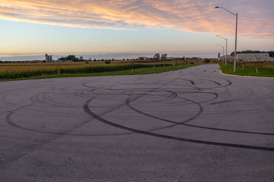 Tire marks and burnout donuts on empty rural road at golden hour dusk