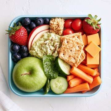 Healthy lunch box snack nut free lunch school snack fresh fruit vegetable sticks cheese cubes whole grain crackers dip balanced meal idea overhead view