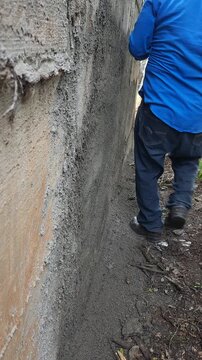 Construction Worker Using Wooden Float to Smooth Cement Plastering on Wall
