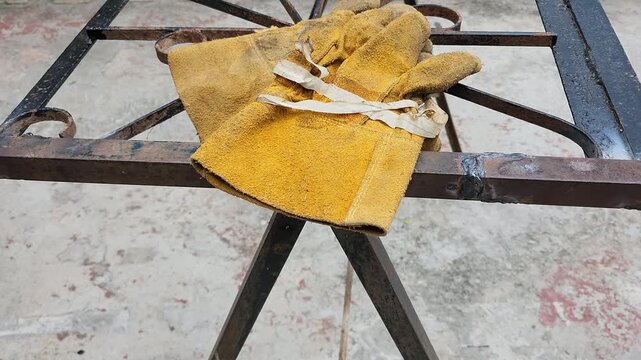 Throwing Worn Leather Work Gloves onto Metal Workbench