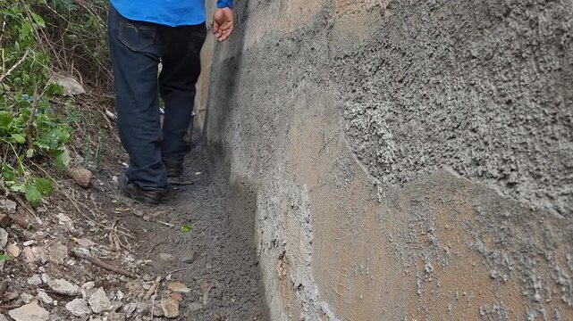 Worker Walking Down Narrow Hallway Preparing Wall for Cement Plastering