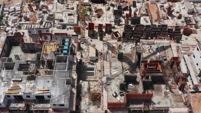 Top down aerial perspective of complex concrete foundation formwork and steel rebar structures at an active urban commercial construction site