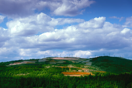 Terraced Farmland and Forest Hills Under Dramatic Cloudy Sky