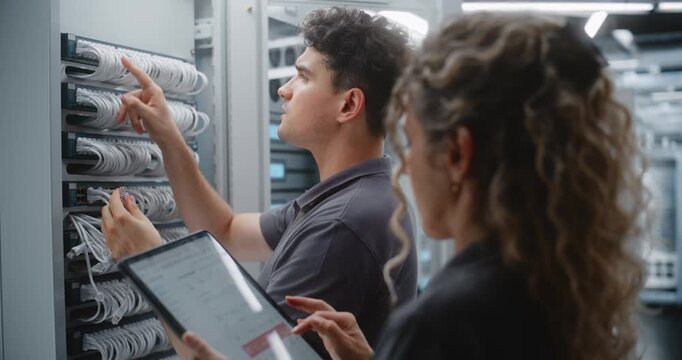 Female IT Engineer Supervises Port Changes on Tablet While Male Technician Reconnects Ethernet Patch Cords, Comparing Live Server Telemetry With Network Procedures During Coordinated Maintenance.