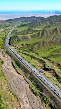 Aerial View of Traffic on Duku Highway Through Green Hills in Xinjiang China