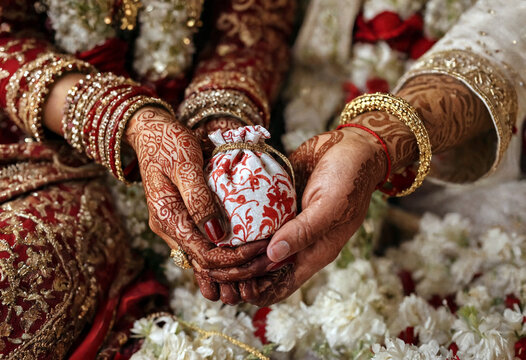 Traditional indian wedding ceremony hands with henna and jewelry holding a decorative pouch