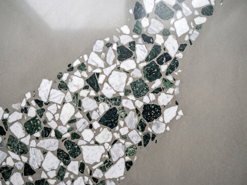 Modern terrazzo flooring detail with green and white marble chips embedded in smooth gray concrete surface