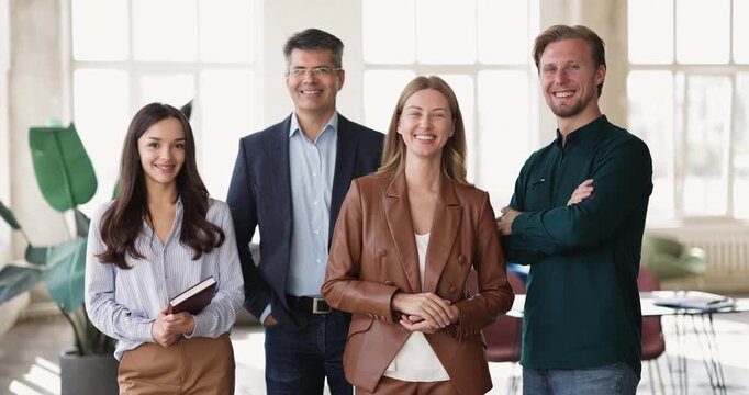 Group portrait smiling confident diverse business professionals standing together in modern office looking at camera representing corporate human resources successful teamwork productive collaboration