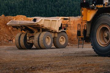 Rear and wheel detail of heavy yellow mining dump truck on dirt road for industrial background and construction design © Parilov