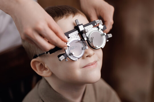 Closeup portrait of boy wearing trial frame during eye test in clinic, doctor help for child