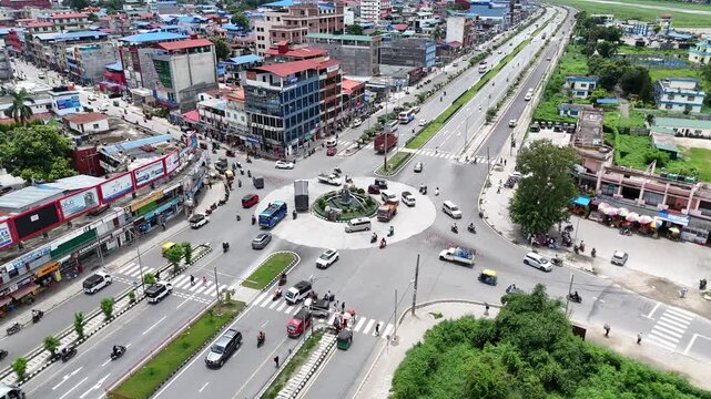 High angle aerial view of a busy traffic roundabout intersecting a major divided highway in a bustling Nepalese commercial district