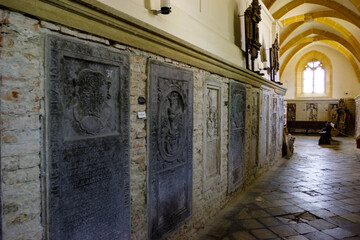 Obraz premium Interior view of a church hallway with stone sarcophagi and a stained glass window.