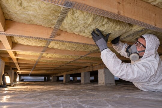 Installer fitting insulation beneath a timber floor