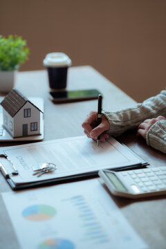 A real estate professional reviews and signs a property agreement, representing a home purchase, mortgage approval, investment, and legal transaction.