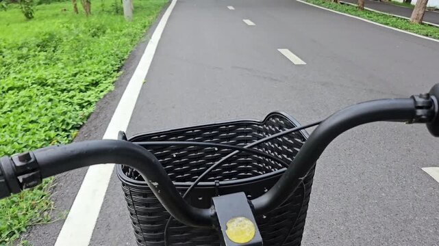 Close-up shot of an unidentified man riding a bicycle on a designated bike path in a lush public park, surrounded by greenery. Concept of a healthy lifestyle, outdoor exercise, and active living