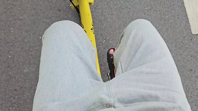 Close-up shot of an unidentified man riding a bicycle on a designated bike path in a lush public park, surrounded by greenery. Concept of a healthy lifestyle, outdoor exercise, and active living