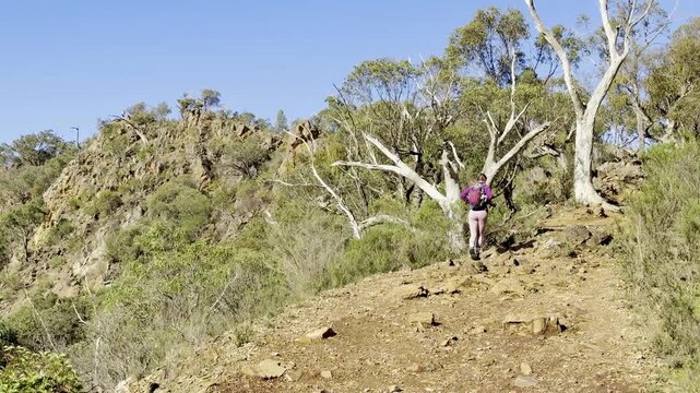 A girl hiker walks and admires the bush and landscape, embracing the adventurous life in Australia, along the Werribee Gorge Circuit Walk, near Melbourne, Victoria, Australia.