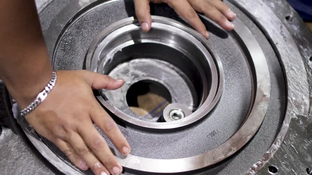 Mechanic installing a hydraulic clutch piston into transmission housing in repair shop.