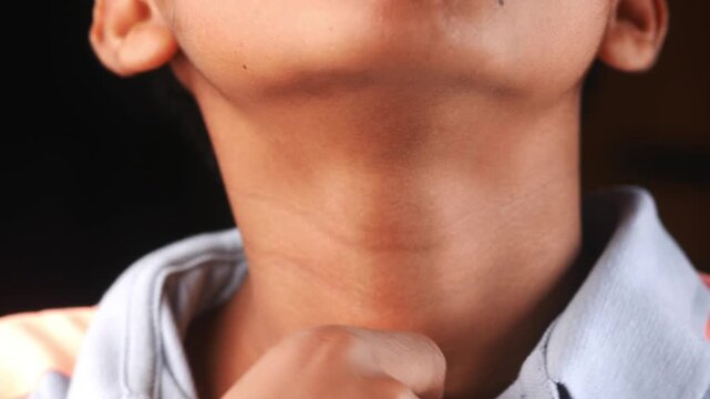 Close up of person touching their neck with fingers to identify pain or swelling during medical examination