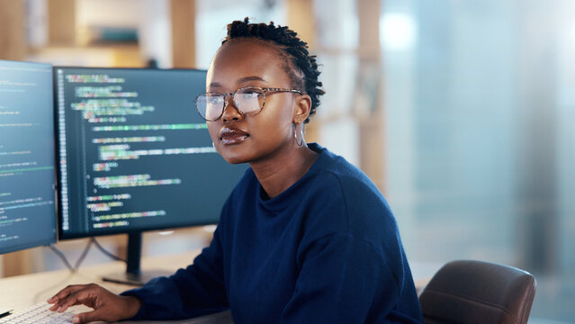 Focused software developer with glasses analyzing code on computer screen in office background banner