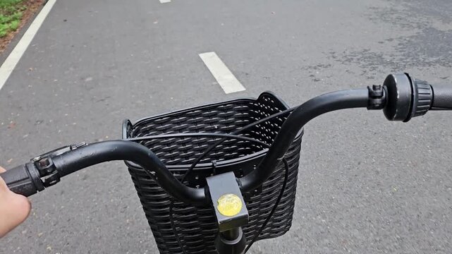Close-up shot of an unidentified man riding a bicycle on a designated bike path in a lush public park, surrounded by greenery. Concept of a healthy lifestyle, outdoor exercise, and active living