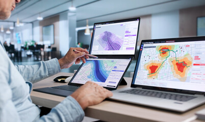 Obraz na płótnie Canvas GIS Analyst Examines Flood Risk Data On Dual Touchscreen Laptop