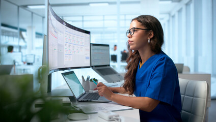Healthcare Technician Updates Patient Records Using Laptop
