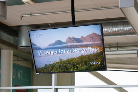 August 19, 2026, Stavanger, Norway - A monitor displaying a scenic Norwegian landscape with Avinor branding and text "Vi s&oslash;rger for at Norge flyr" at Stavanger Airport.