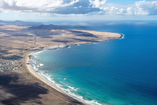 View from above, coast with Playa Famara and sea with the town of Caleta de Famara, Lanzarote, Canary Islands, Spain